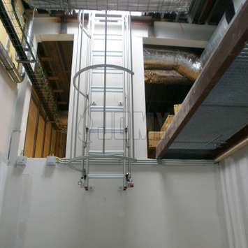 Austarierte untere Schiebeleiter mit Käfig in industrieller Umgebung.