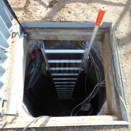 Escalera de pozo equipada con un mango telescópico para entrada y salida segura al pozo. 