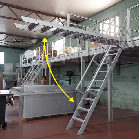 Escalera retráctil para altillo montada sobre resortes de gas y utilizada para acceder a un entrepiso industrial.